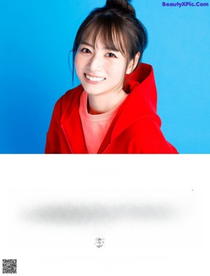 A woman in a red hoodie smiles at the camera.