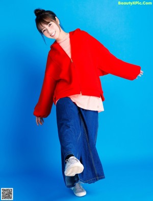 A woman in a red hoodie smiles at the camera.