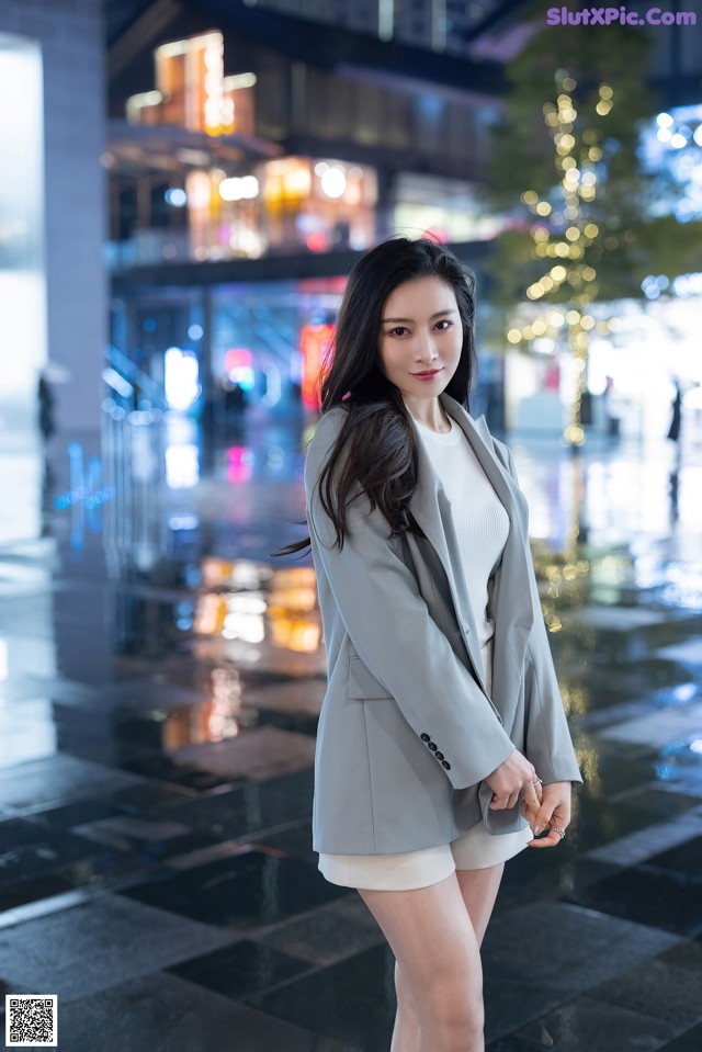 A woman in a gray blazer and white shorts posing for a picture.