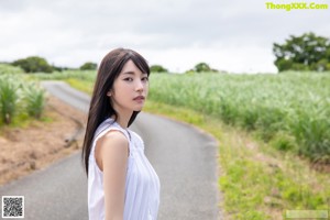 A woman in a white dress standing next to a sign.