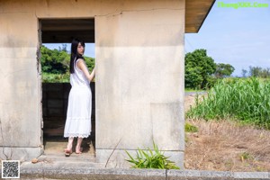 A woman in a white dress standing in a field of sugarcane.