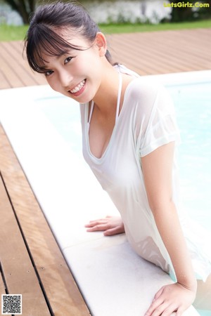 A woman in a blue and white bikini sitting on a dock.