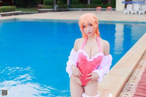 A woman in a pink bathing suit sitting by a pool.