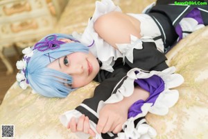 A woman in a maid outfit sitting on a couch.