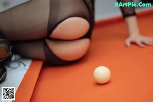 A woman sitting on top of a pool table.