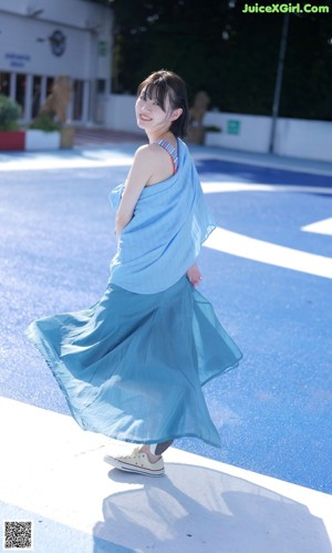 A woman in a blue dress is walking on a blue surface.