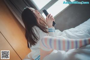 A woman sitting on a bed with her eyes closed.