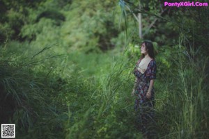 A naked woman standing in the middle of a forest.