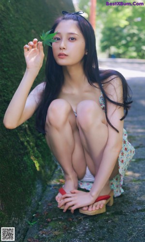 A woman in a white bikini sitting on a tatami mat.