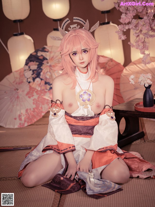 A woman in a kimono sitting on the floor with an umbrella.