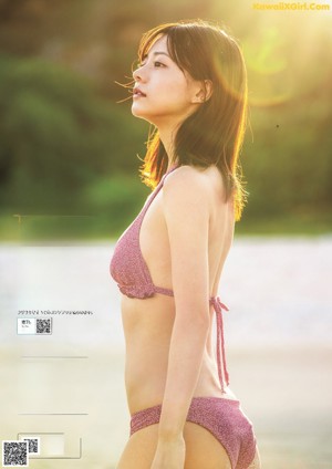 A woman in a yellow bikini with a towel over her head.