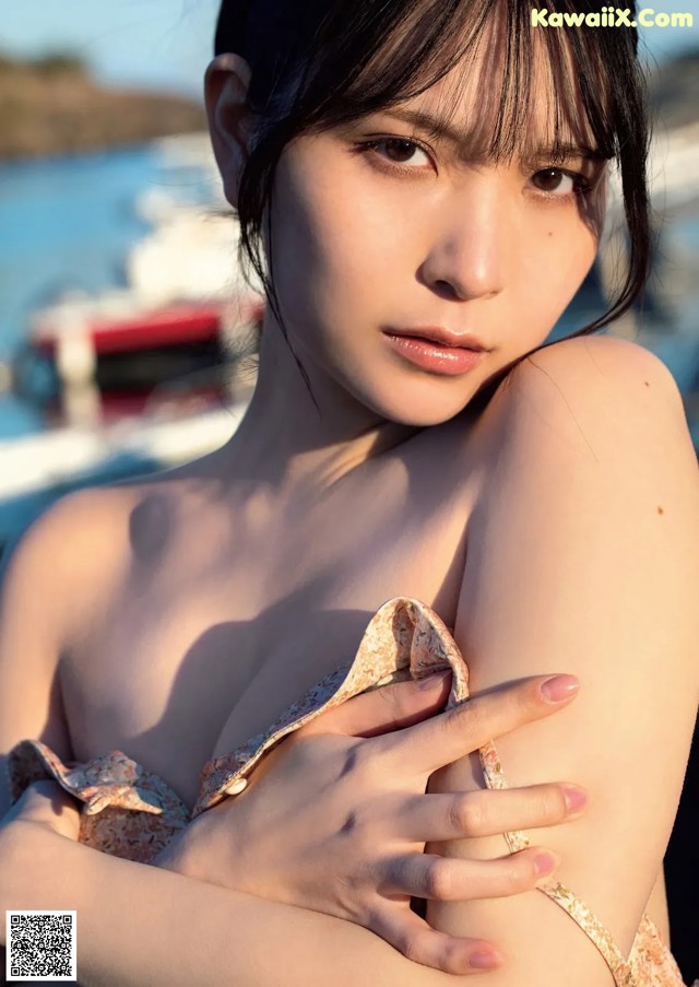 A woman in a bikini posing by the water.