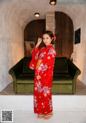 A naked asian woman sitting on a red couch.