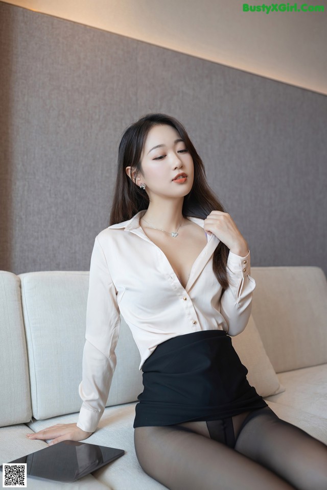 A woman sitting on a couch holding a tablet computer.