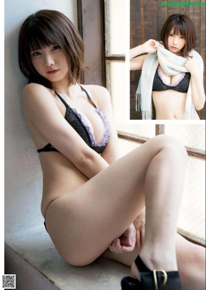 A woman in a black bra and panties sitting on a bed.