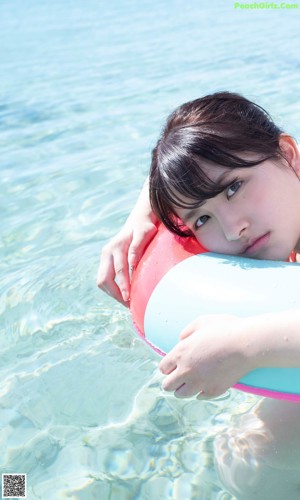 A woman in a pink bikini laying on an inflatable ring in a pool.