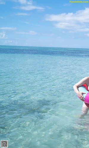 A woman in a pink bikini sitting on a white chair.