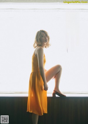 A woman in a bathing suit posing in front of a window.