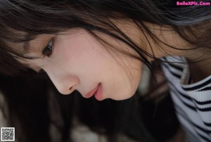 A woman with long black hair wearing a striped shirt.