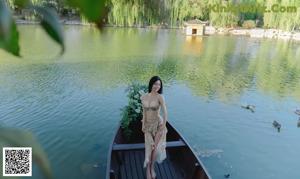 A woman sitting on a wooden bench next to a body of water.