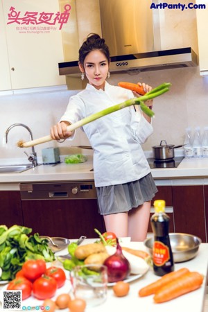 A woman holding an apple and a carrot in a kitchen.