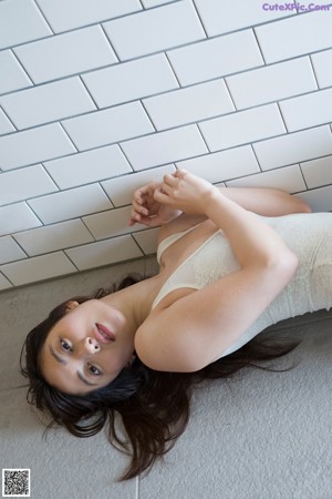 A woman in a white lingerie leaning against a window.