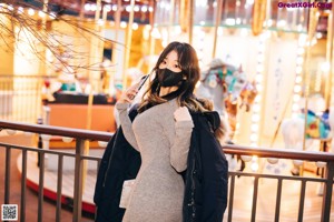 A woman wearing a face mask standing on a railing.