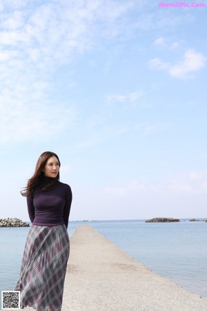 A woman in a purple sweater is posing for the camera.