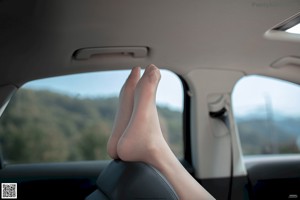 A woman sitting in the back seat of a car with her legs crossed.