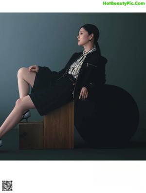 A woman in a black dress holding a white bag.