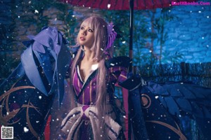 A woman in a blue and purple kimono sitting on a bed.