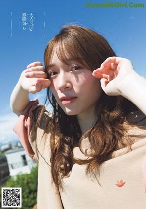 A woman leaning against a wall with her arms outstretched.