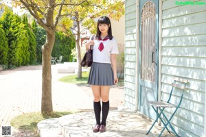 A woman in a school uniform is posing for a picture.