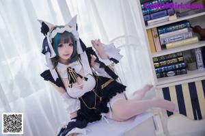 A woman in a maid outfit sitting on a chair.