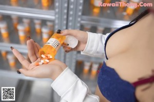 A woman in a white lab coat sitting at a counter in a pharmacy.