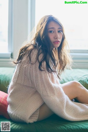 A woman sitting on a green couch holding a lollipop.