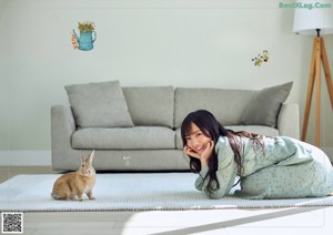 A young girl in a pink bunny costume peeking out from behind a blanket.