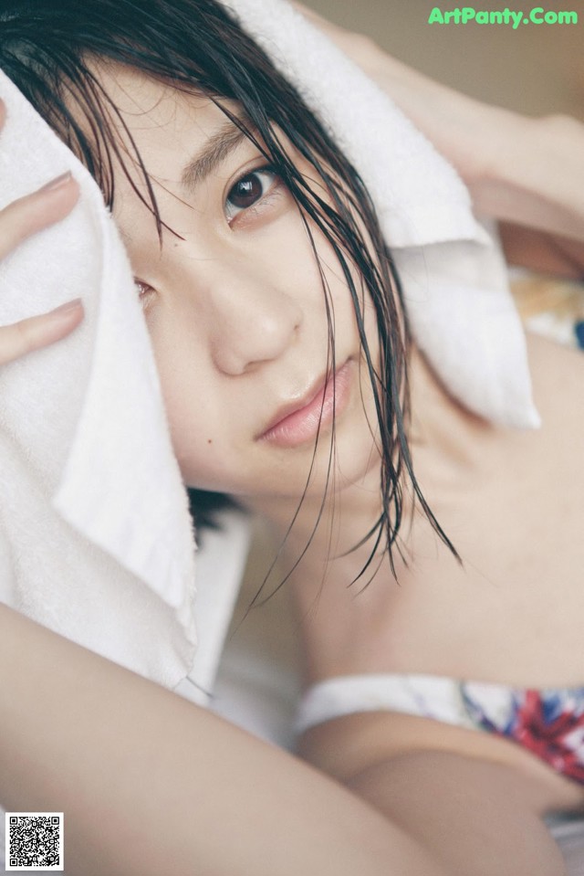 A woman laying on a bed with a towel over her head.