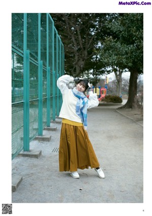 A young woman in a yellow sweater is smiling at the camera.