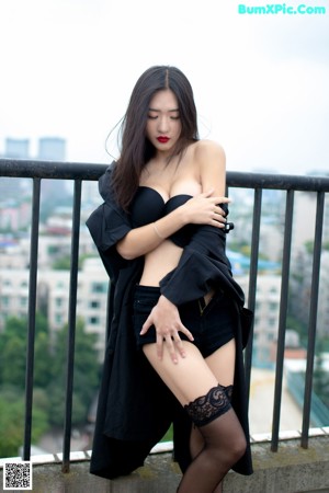 A woman in a white shirt and blue shorts posing on a roof.