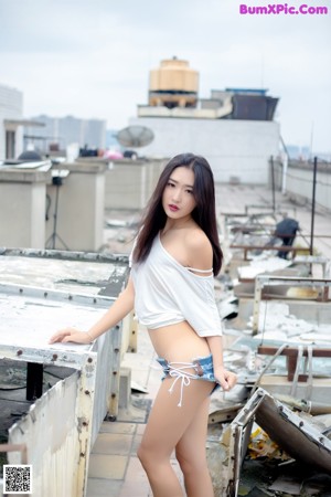 A woman in a black bra and skirt sitting on a ledge.