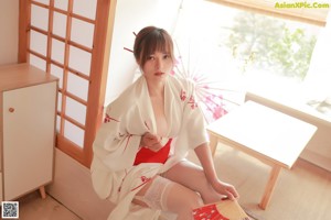 A woman in a red bikini sitting on a table with an umbrella.